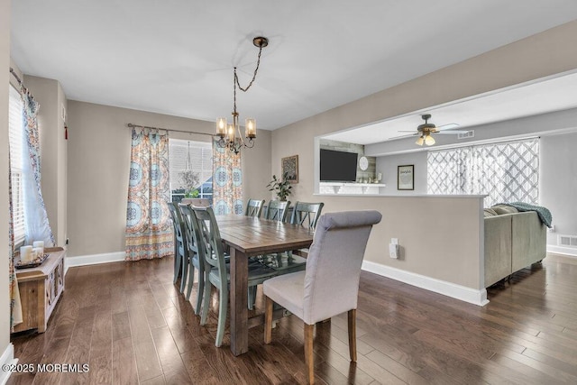 dining area featuring visible vents, ceiling fan with notable chandelier, dark wood-type flooring, and baseboards