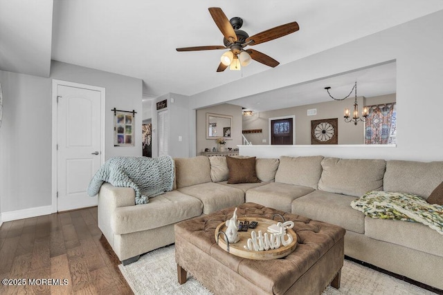 living room featuring baseboards, wood finished floors, and ceiling fan with notable chandelier