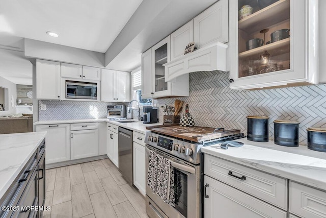 kitchen featuring white cabinetry, light stone counters, appliances with stainless steel finishes, and a sink