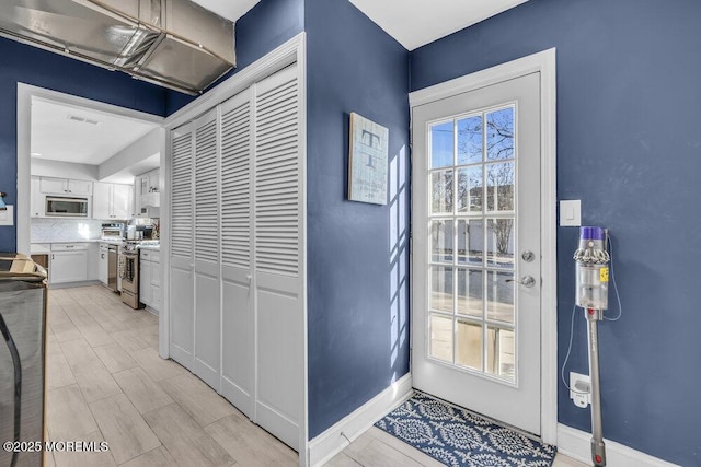 doorway featuring plenty of natural light, visible vents, baseboards, and wood finish floors