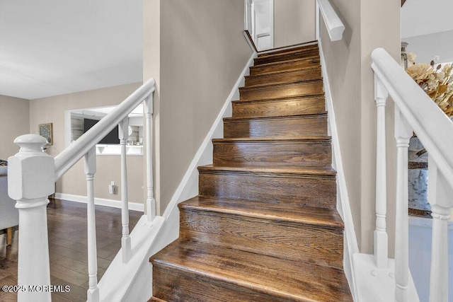 staircase featuring wood finished floors and baseboards