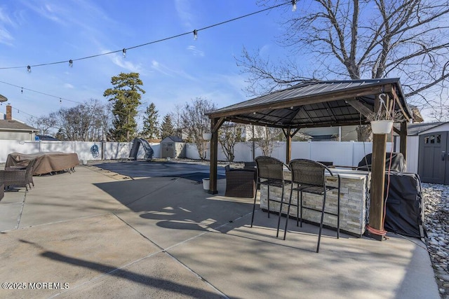 view of patio / terrace with an outbuilding, a shed, a gazebo, and a fenced backyard