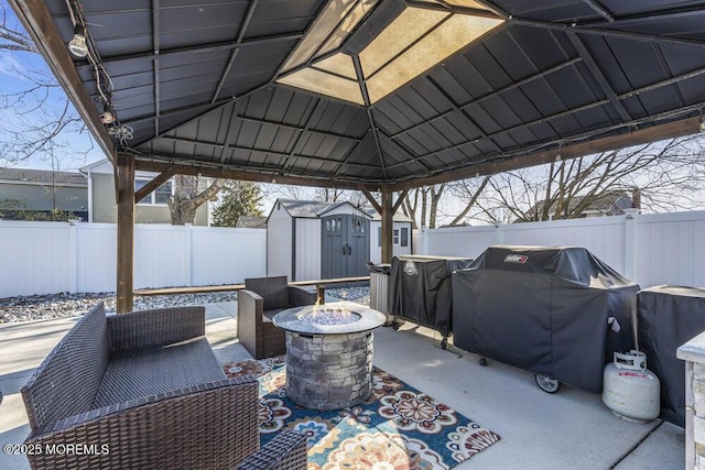 view of patio with an outbuilding, area for grilling, a fenced backyard, a fire pit, and a storage shed