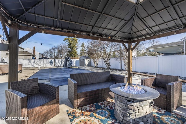 view of patio / terrace featuring a fenced backyard, a gazebo, a fire pit, a storage shed, and an outdoor structure