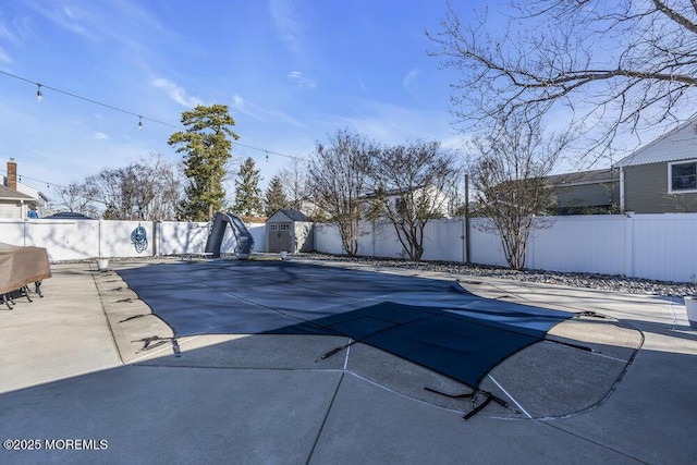 view of pool with an outdoor structure, a fenced backyard, a shed, and a patio