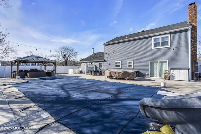 rear view of property with a fenced in pool, a gazebo, a chimney, a fenced backyard, and a patio