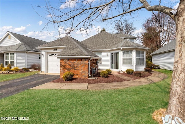 view of front of house featuring aphalt driveway, a front yard, a shingled roof, a garage, and brick siding