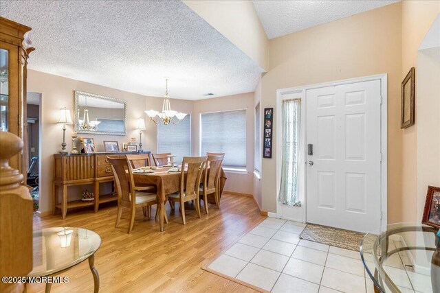 interior space with an inviting chandelier, baseboards, light wood finished floors, and a textured ceiling