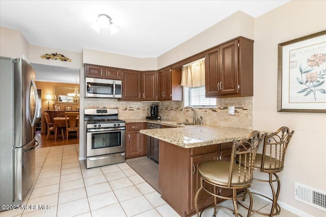 kitchen with visible vents, decorative backsplash, appliances with stainless steel finishes, a peninsula, and a sink