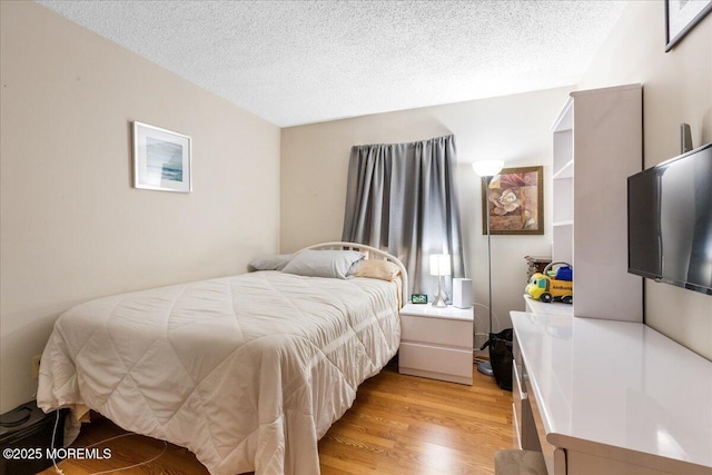 bedroom featuring light wood finished floors and a textured ceiling