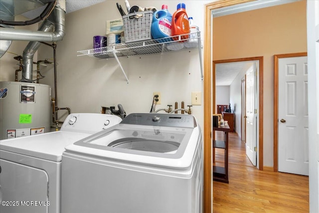 laundry area with light wood-style flooring, washing machine and dryer, laundry area, and water heater