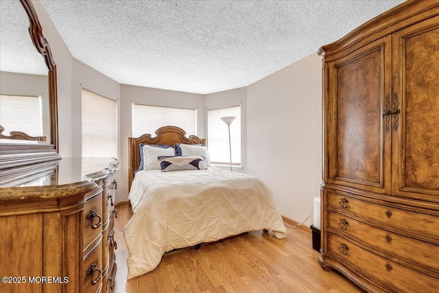 bedroom with light wood-style floors and a textured ceiling