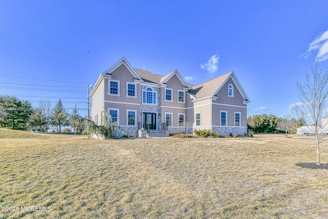 view of front of property with a front yard, stone siding, and stucco siding