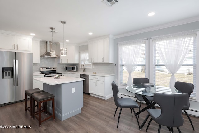 kitchen with visible vents, a sink, a center island, appliances with stainless steel finishes, and wall chimney exhaust hood