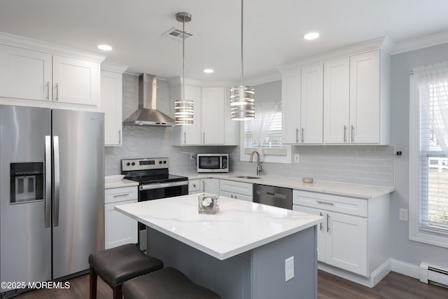 kitchen with visible vents, wall chimney range hood, baseboard heating, plenty of natural light, and stainless steel appliances