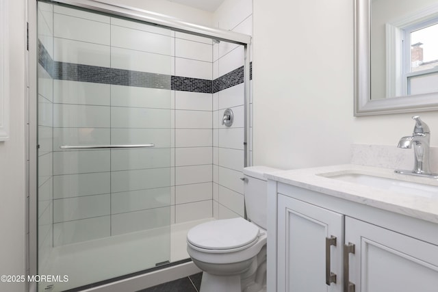 bathroom featuring vanity, toilet, and a shower stall