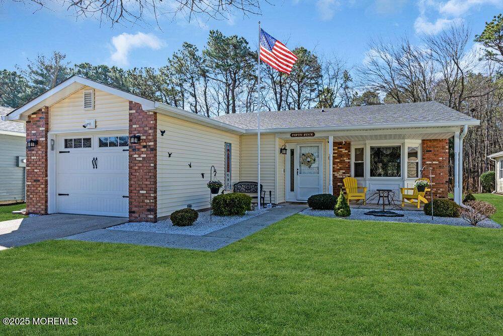 view of front of home featuring aphalt driveway, roof with shingles, a front yard, a garage, and brick siding