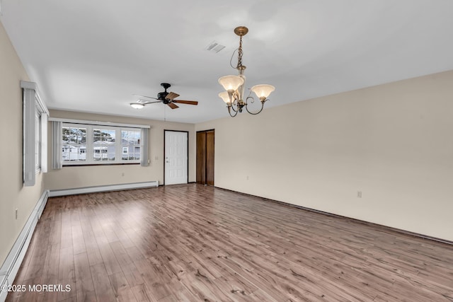 empty room featuring baseboard heating, ceiling fan with notable chandelier, visible vents, and wood finished floors