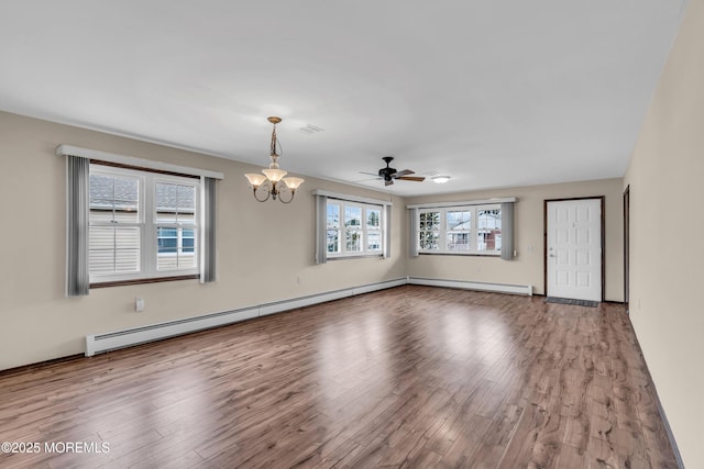 spare room with ceiling fan with notable chandelier, wood finished floors, visible vents, and a baseboard radiator