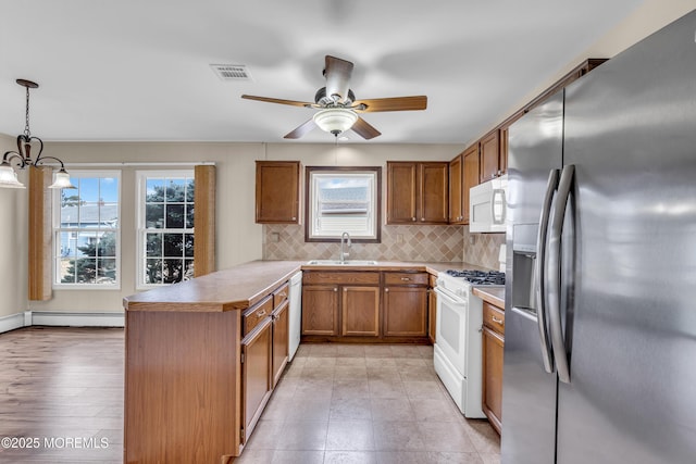 kitchen with white appliances, brown cabinets, a peninsula, a sink, and tasteful backsplash