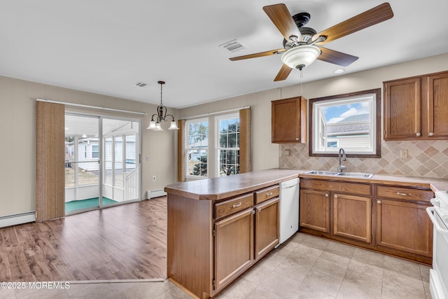 kitchen with a sink, a baseboard heating unit, white appliances, a peninsula, and brown cabinetry