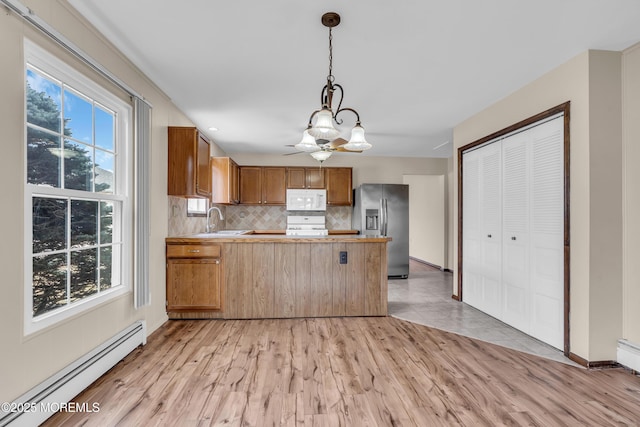 kitchen featuring light wood-style flooring, a baseboard heating unit, a peninsula, stainless steel fridge with ice dispenser, and white microwave