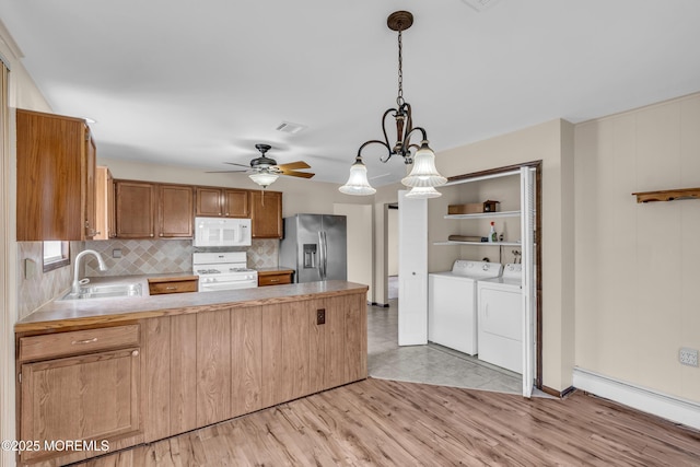 kitchen featuring visible vents, washing machine and dryer, a peninsula, white appliances, and a sink