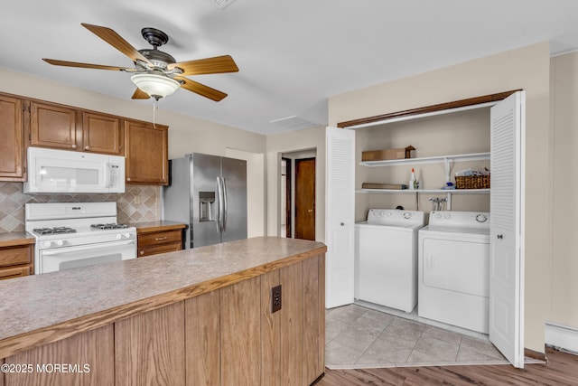 kitchen with white appliances, a ceiling fan, decorative backsplash, light countertops, and washing machine and dryer