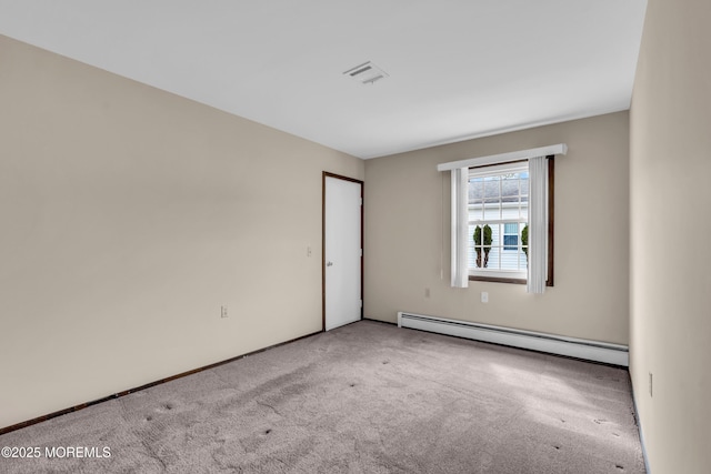 spare room featuring a baseboard heating unit, carpet floors, and visible vents