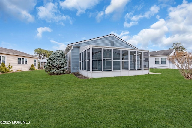 rear view of house featuring a yard and a sunroom