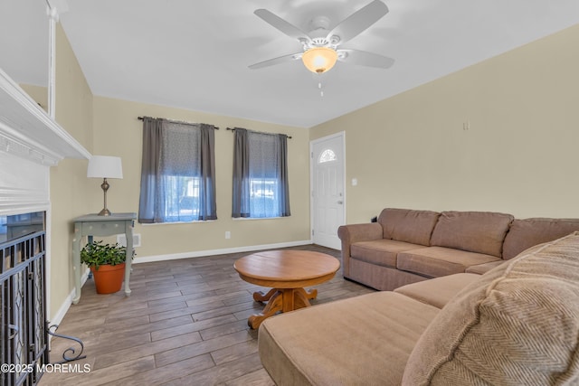 living room with baseboards, a fireplace, wood finished floors, and a ceiling fan