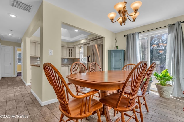 dining area with visible vents, a notable chandelier, baseboards, attic access, and wood tiled floor