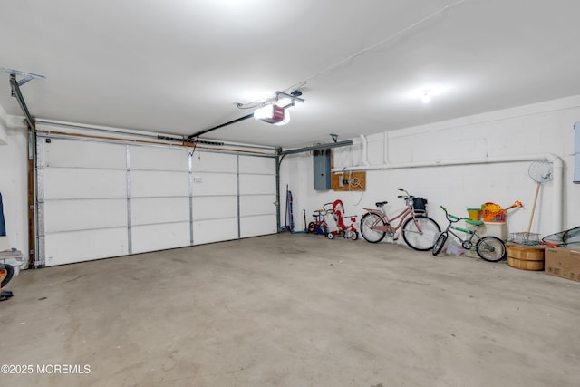 garage with electric panel, a garage door opener, and concrete block wall