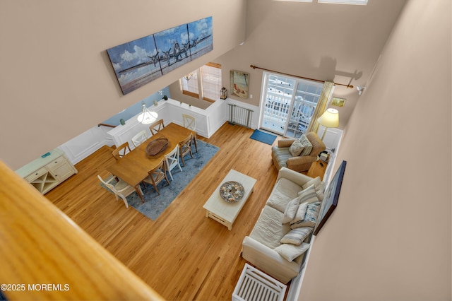 living area with radiator, a high ceiling, and wood finished floors