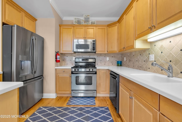 kitchen with light wood-style flooring, stainless steel appliances, ornamental molding, and a sink