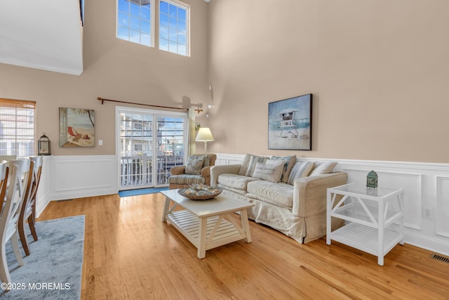 living area with plenty of natural light, wainscoting, and light wood-type flooring