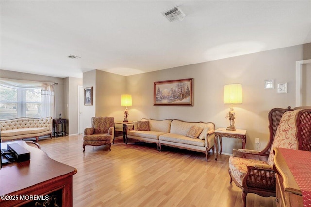 living room with visible vents, baseboards, and light wood-style floors