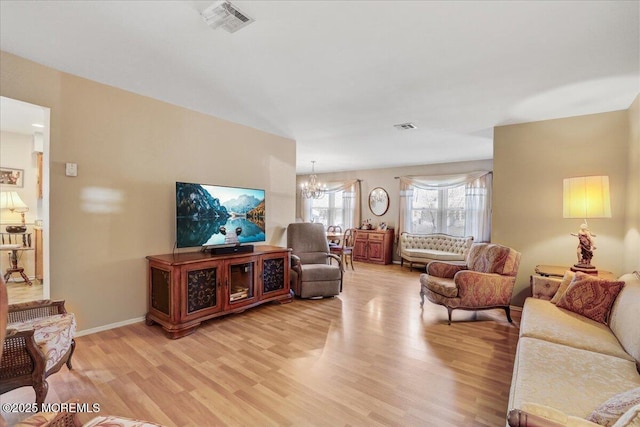 living area with visible vents, baseboards, an inviting chandelier, and light wood-style flooring