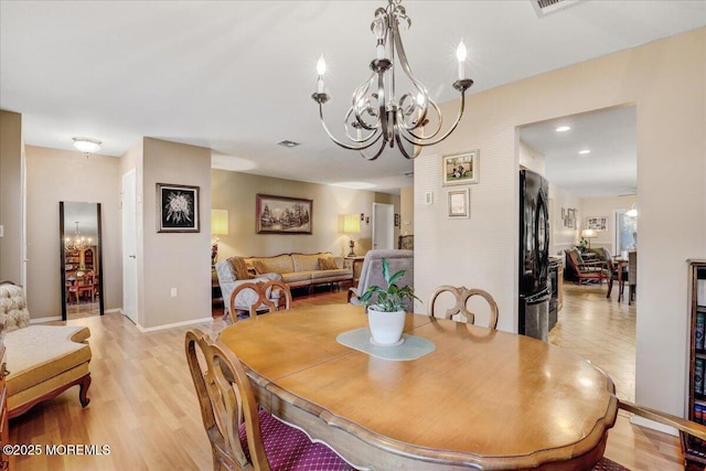 dining area featuring light wood-type flooring, baseboards, visible vents, and a chandelier