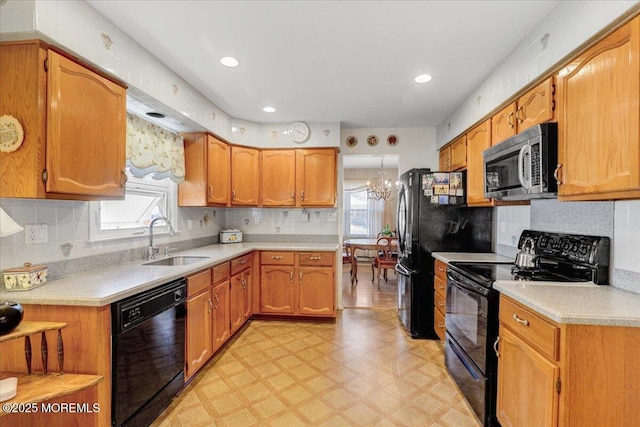 kitchen with a wealth of natural light, black appliances, a sink, light countertops, and light floors