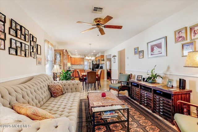 living room with visible vents and ceiling fan with notable chandelier