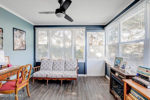 interior space with baseboards, wood finished floors, a ceiling fan, and ornamental molding