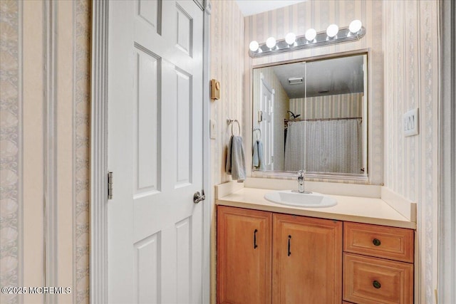 full bath with a shower with curtain, vanity, and wallpapered walls