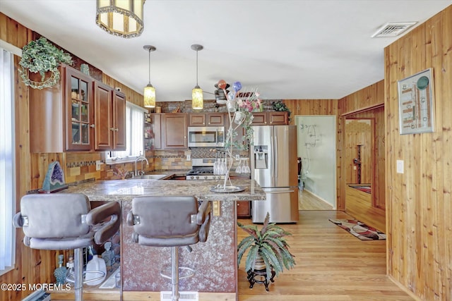 72 Mount Matterhorn Ln, Toms River, NJ 08753 - kitchen featuring visible vents, a sink, a peninsula, appliances with stainless steel finishes, and wood walls