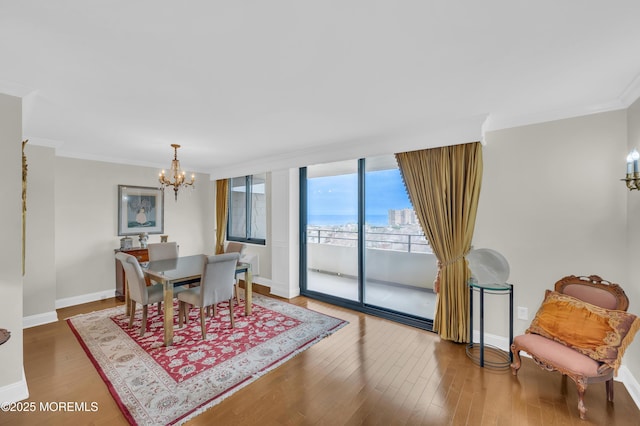 dining area with a notable chandelier, wood finished floors, baseboards, and ornamental molding