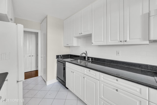 kitchen featuring a sink, black dishwasher, freestanding refrigerator, white cabinets, and light tile patterned flooring