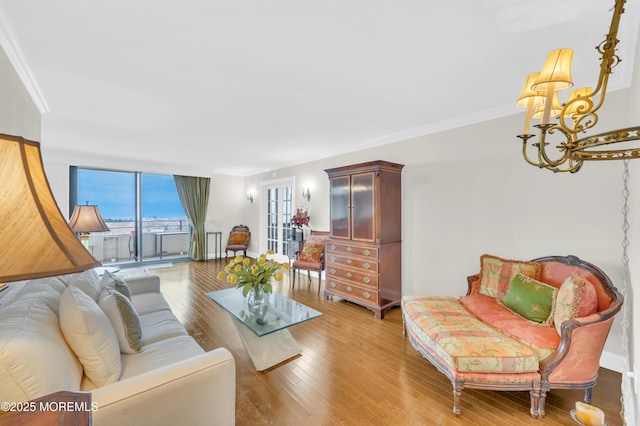 living area with crown molding, baseboards, a chandelier, light wood-type flooring, and expansive windows