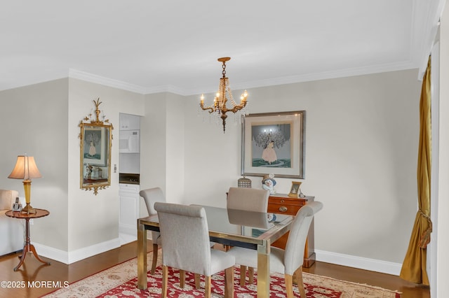 dining area with baseboards, an inviting chandelier, and wood finished floors