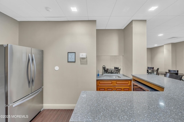 kitchen with baseboards, freestanding refrigerator, a sink, dark wood-type flooring, and brown cabinets