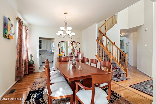 dining area featuring visible vents, light wood-style floors, a chandelier, and stairs